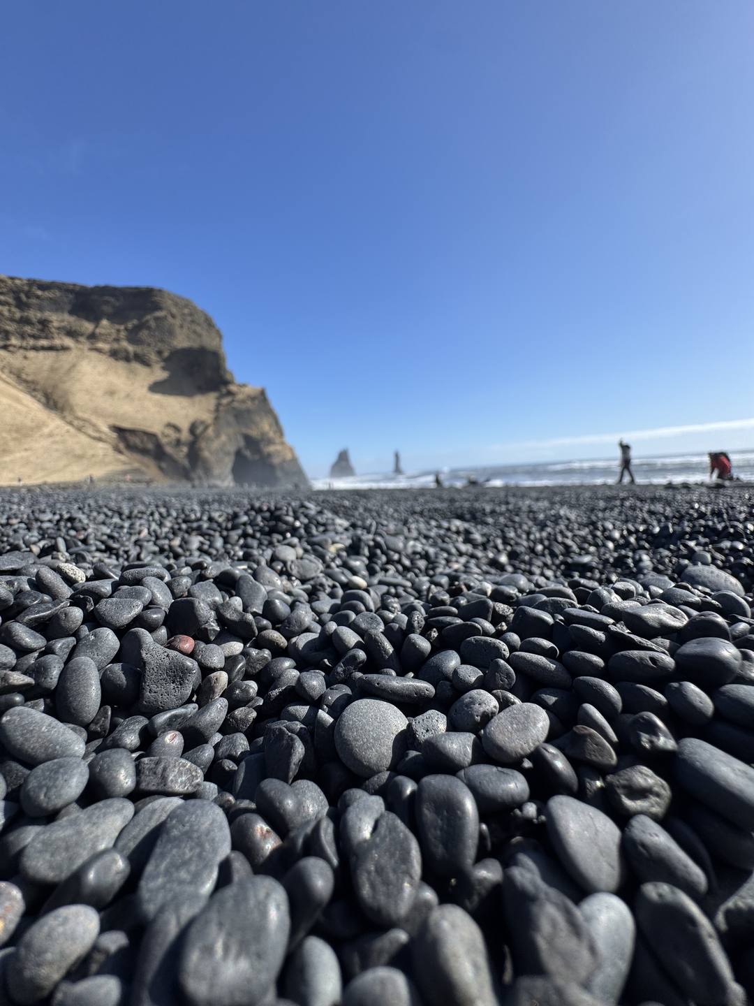 Basalt pebbles and the Reynisdrangar sea stacks at Reynisfjara black sand beach
