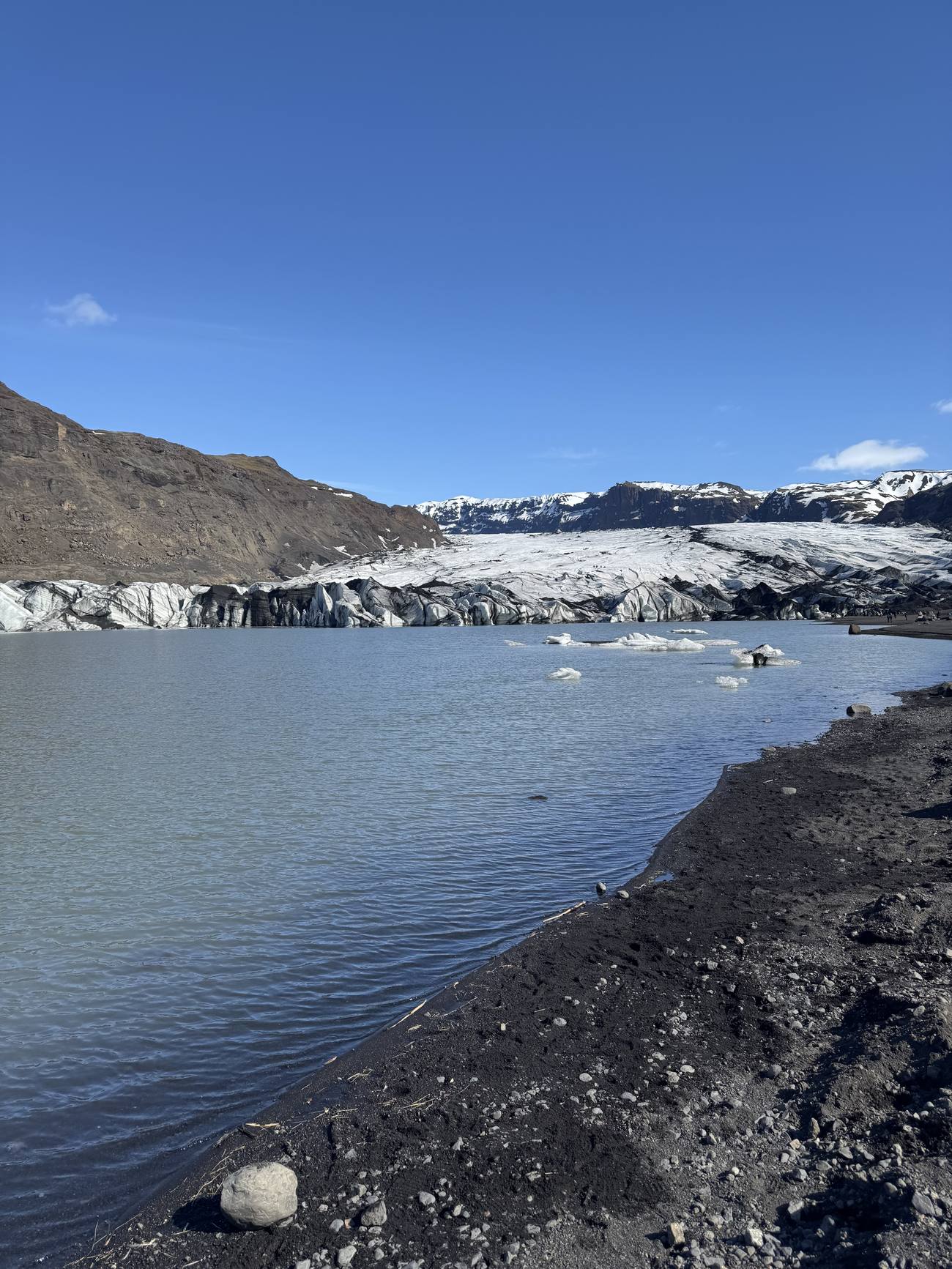 Sólheimajökull glacier tongue meeting a grey meltwater lagoon on Iceland's South Coast